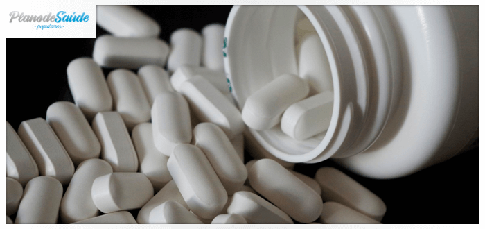 Frasco com comprimidos espalhados em uma mesa - coronavírus