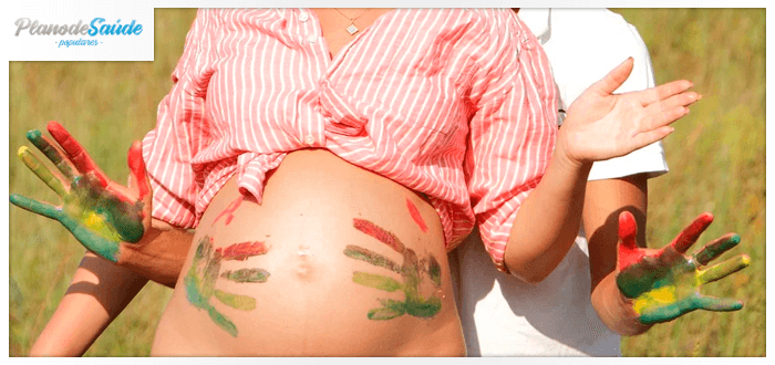 Homem sujando a barriga de grávida com tinta - parto humanizado