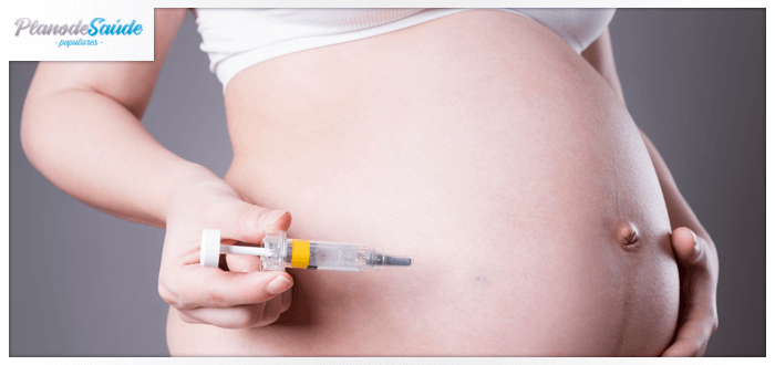 Mulher grávida segurando seringa vazia próximo à barriga - Trombofilia na Gravidez